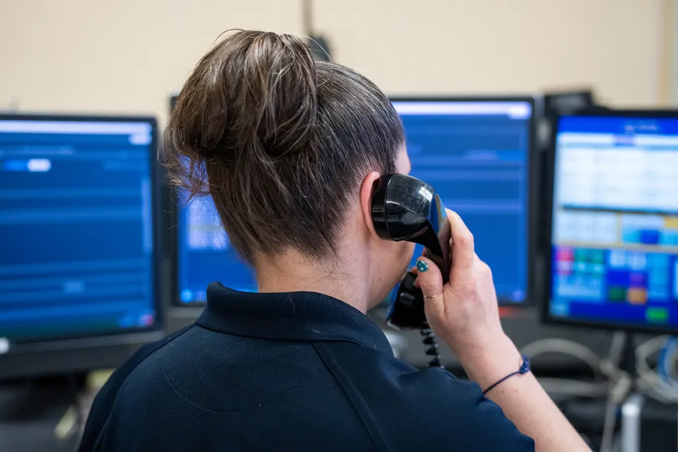 A member of the UPD Dispatch team holds a phone up to her hear to take a call in the Communications Center.